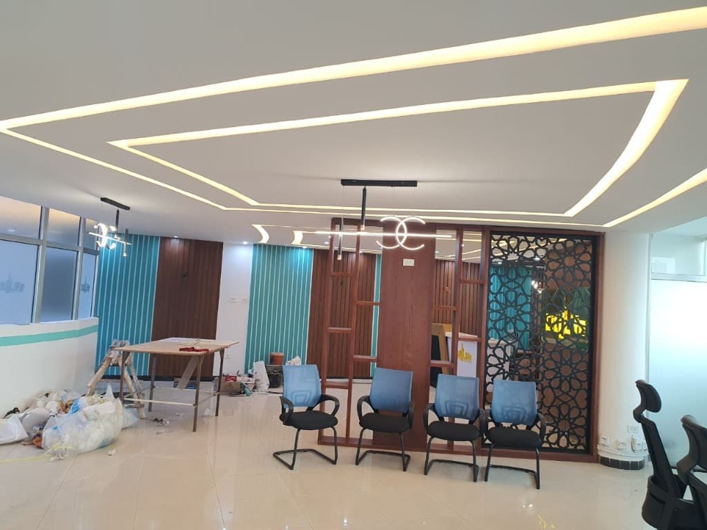 Executive reception lounge with multi-tiered geometric cove ceiling lighting.