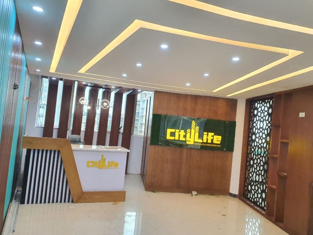 Completed executive reception counter with vertical timber fluting and backlit City Life corporate signage.